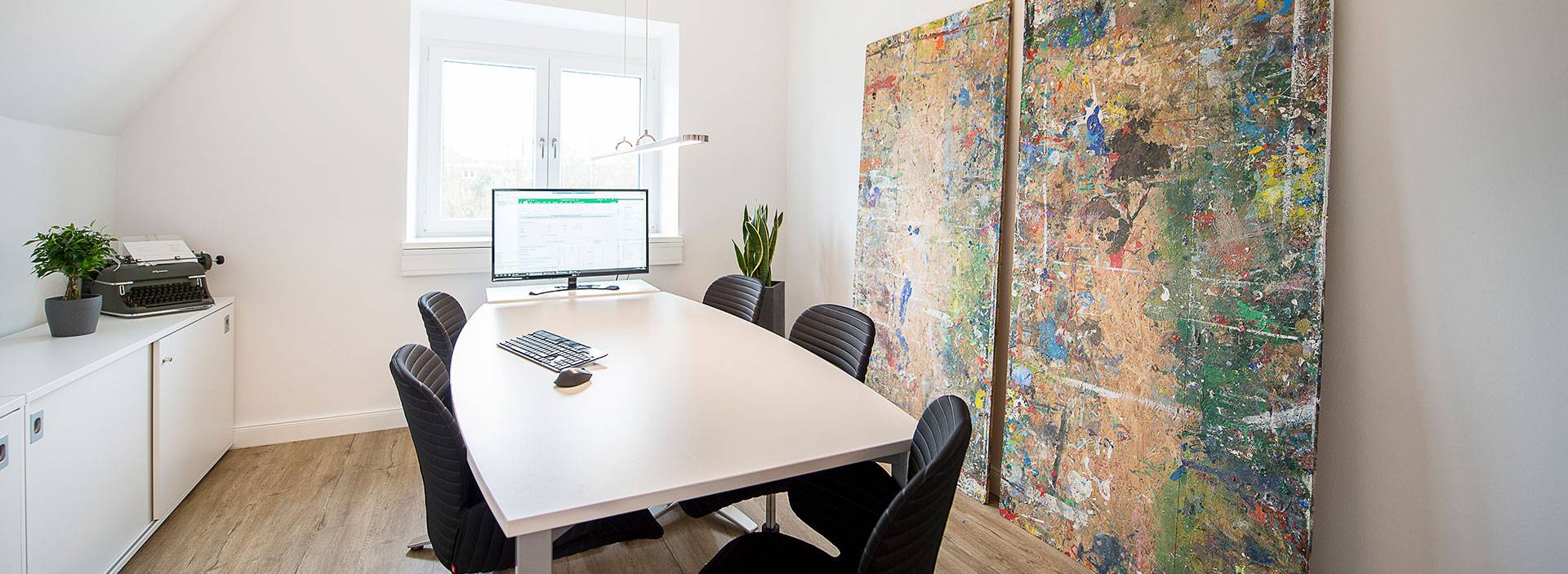 Büro mit Konferenztisch und großen Wandgemälden